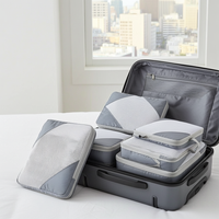 Set of gray and white packing cubes in an open suitcase with a cityscape in the background.