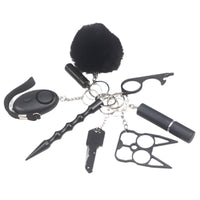 8-piece women’s self-defense keychain set in silver, including alarm, self-defense stick, window breaker, whistle, knife, knuckle tool, bottle holder, and pompom—all arranged neatly for display.