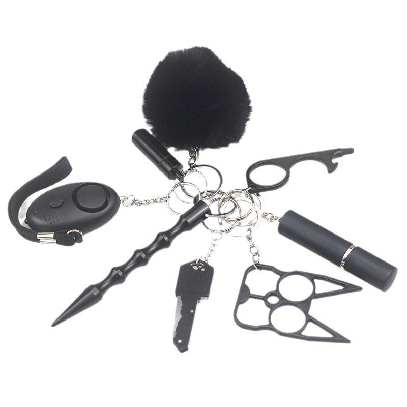 8-piece women’s self-defense keychain set in silver, including alarm, self-defense stick, window breaker, whistle, knife, knuckle tool, bottle holder, and pompom—all arranged neatly for display.