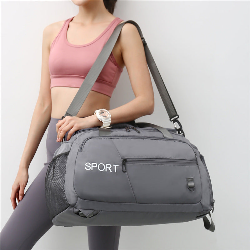 A woman holding a large capacity sports bag in gray color with multiple compartments, featuring a shoulder strap and the text 'SPORT' on the front.