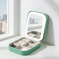 Green makeup box with LED mirror on a white surface near a window with cityscape view