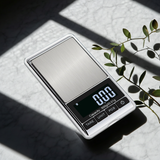 Digital pocket scale on a light surface with a plant in the background
