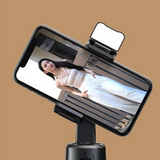  A200 Intelligent Face Tracking Phone Stand in black, showing AI-powered 360º rotation, gesture control, warm LED light, and built-in selfie stick for hands-free video recording showing a woman taking a video of herself whilst traveling solo.