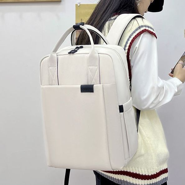 Female woman wearing a white minimalistic aesthetic backpack against a plain background