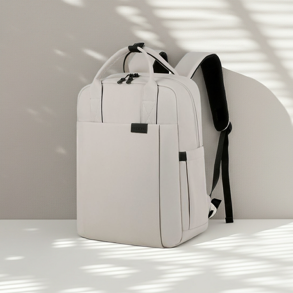 White minimalistic backpack with black straps on a light surface with shadows