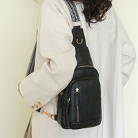 Woman carrying a black retro cross body bag over one shoulder wearing a white coat by the airport