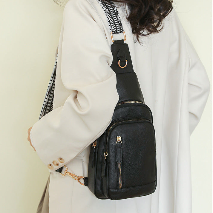 Woman carrying a black retro cross body bag over one shoulder wearing a white coat by the airport