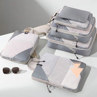 Set of gray compression packing cubes with sunglasses on a light surface