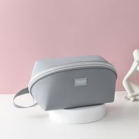 A gray travel underwear organizer bag made from Oxford cloth, displayed against a pink background.