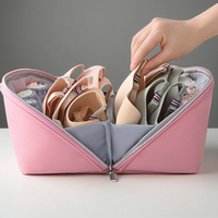 Pink travel organizer with neatly folded underwear and a hand reaching in to adjust items.