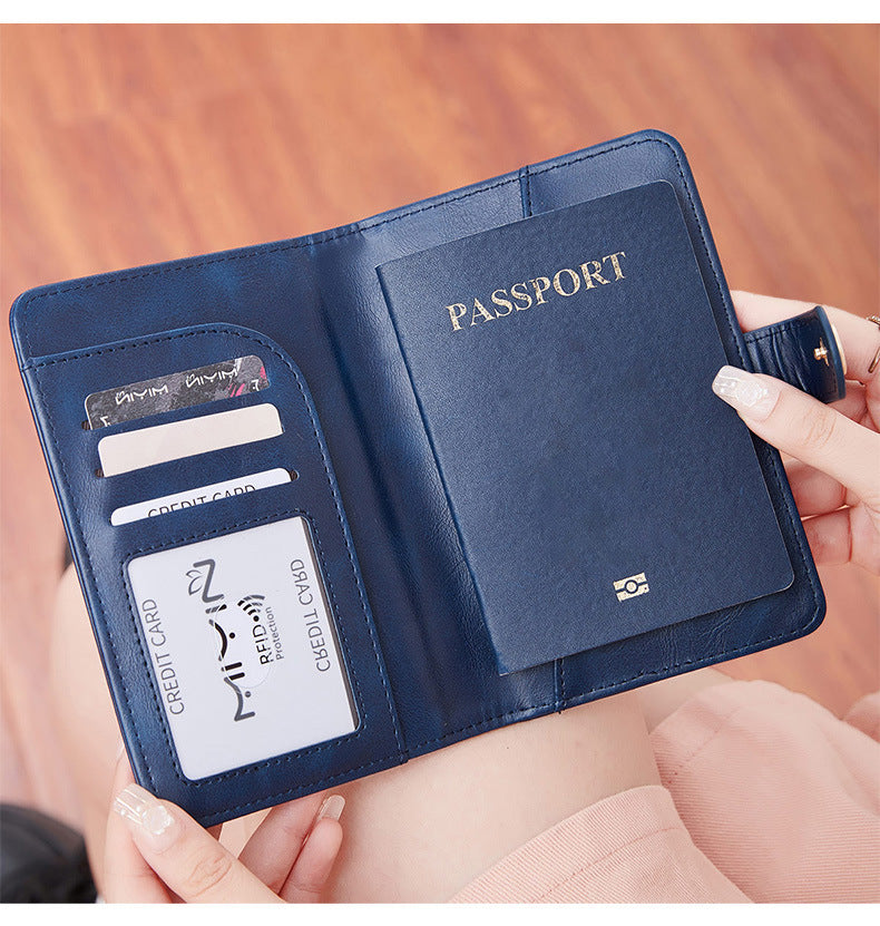 Woman holding a blue travel wallet passport cover with airplane emblem held by a hand against a neutral background