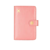 Pink leather travel passport valuables organizer with gold airplane emblem and button on a white background