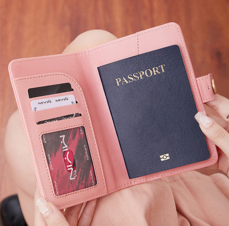 Woman holding a pink travel wallet passport cover with airplane emblem held by a hand against a neutral background