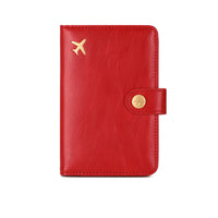 Red leather travel passport valuables organizer with gold airplane emblem and button on a white background