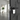 A white hotel door anti-theft alarm with a magnetic sensor and a pull cord on a black door with a blurred room in the background