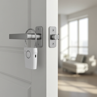 A white hotel door anti-theft alarm with a magnetic sensor and a pull cord on a door handle with a blurred room in the background