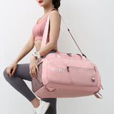 A woman holding a large capacity sports travel bag in pink color with multiple compartments, featuring a shoulder strap and the text 'SPORT' on the front.