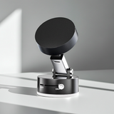 Foldable magnetic phone holder in black, combining vacuum suction and magnetic grip, compatible with most smartphones, shown mounted on dashboard for hands-free use.