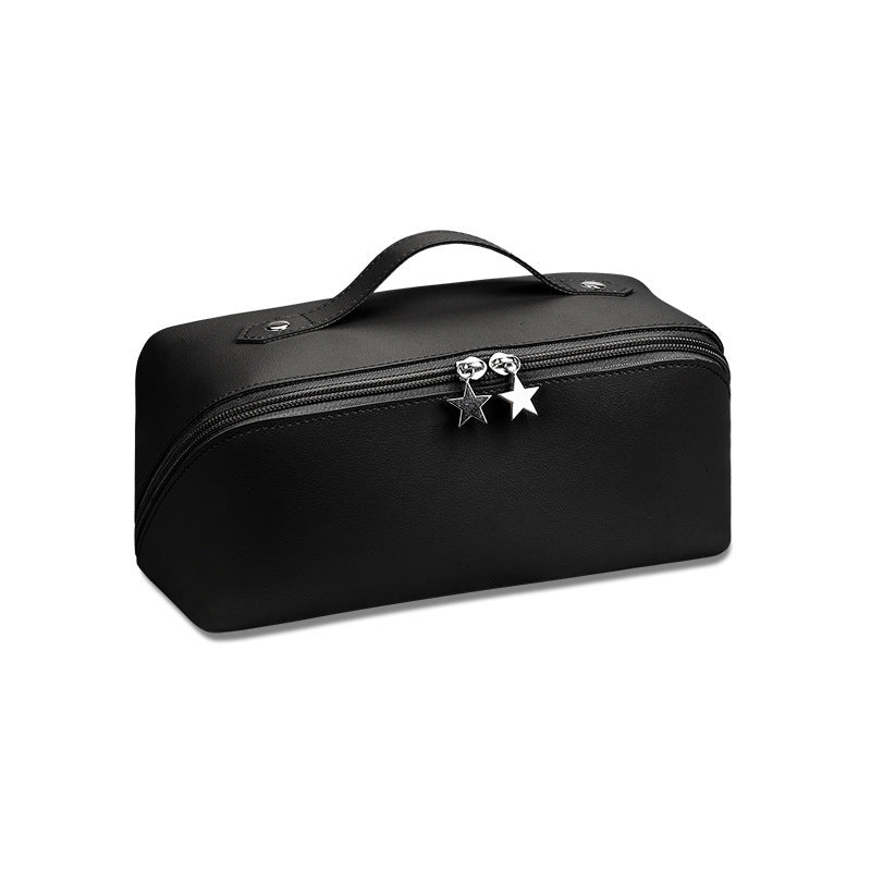 A cosmetics beauty travel organizer in a black color with a zipper closure and a decorative star charm.