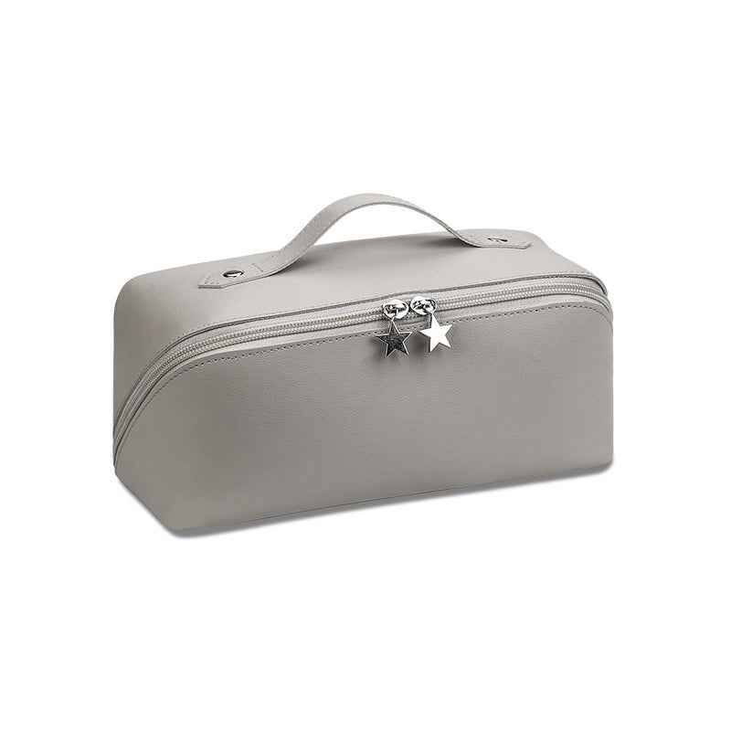 A cosmetics beauty travel organizer in a gray color with a zipper closure and a decorative star charm.