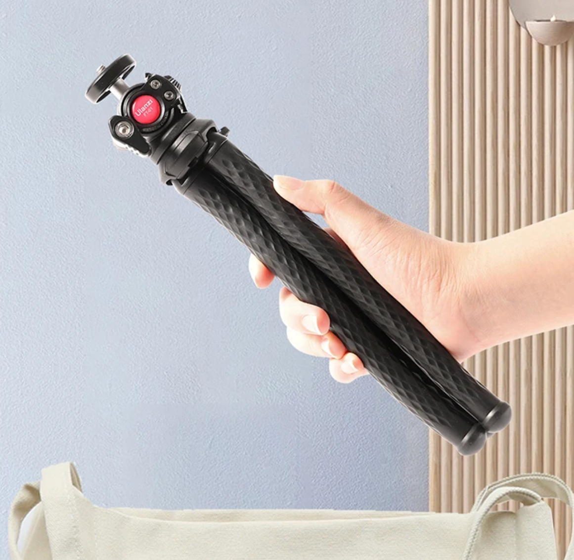Womans hand holding the octopus phone dslr flexible tripod - Flexible black phone selfie octopus tripod with bendable legs and phone clip, shown in a modern minimalist setup for travel and content creation.