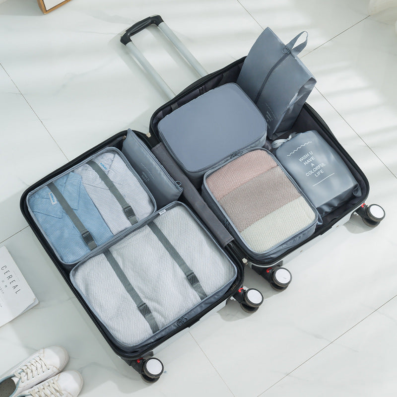 Open suitcase with gray packing cubes organizers inside on a light wooden floor.