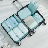 Black suitcase with light blue packing cube organizers on a white floor.
