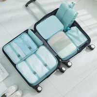 Black suitcase with light blue packing cube organizers on a white floor.