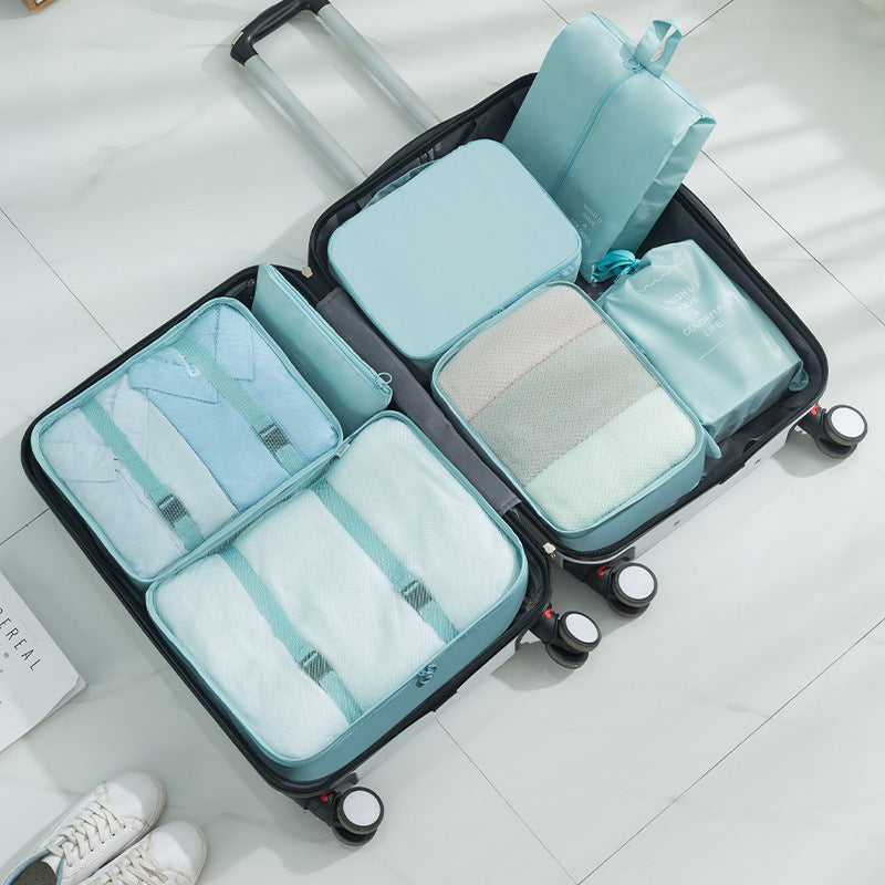 Black suitcase with light blue packing cube organizers on a white floor.