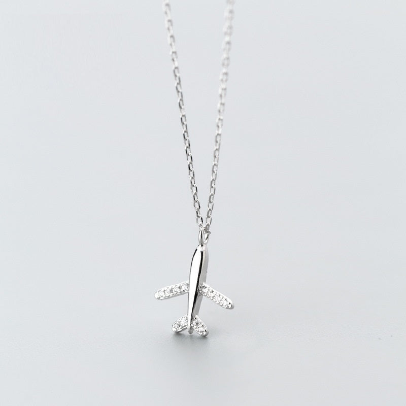 A silver necklace with a pendant in the shape of an airplane, adorned with zirconia stones, displayed against a white background.