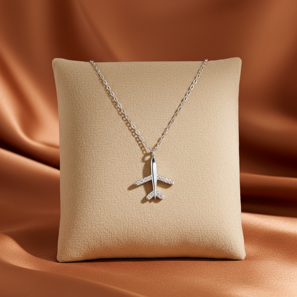 silver zirconia stone airplane pendant necklace on a silk beige pillow