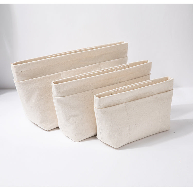 Three beige cotton canvas bag organizers with different sizes displayed against a white background. Beige cotton canvas bag organizer with multiple pockets, Japanese minimalist design, available in drawstring or zipper closure, shown in small/medium/large sizes.