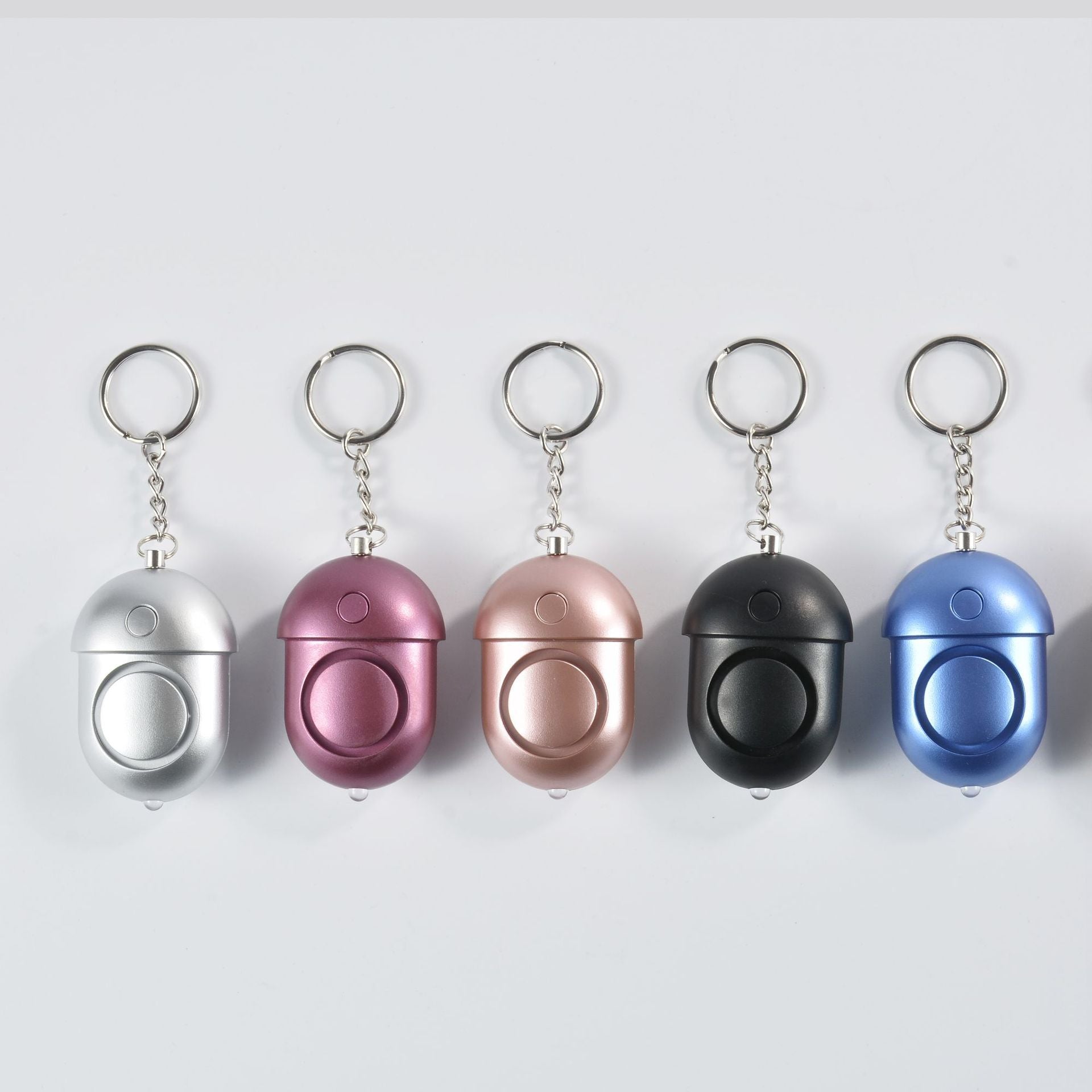 Mini personal safety alarms displayed in multiple colors: black, silver, purple, rose gold, blue.