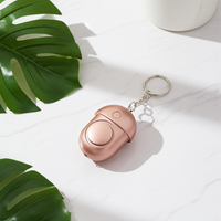 Mini self-defense alarm in rose gold pink, compact keychain safety device with built-in LED light, shown in modern minimalist style.